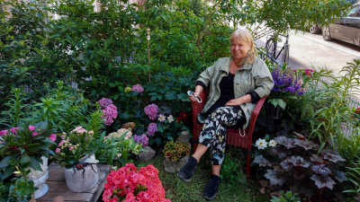 Margot Leinonen istuu taloyhtiön pihalle tekemässään puutarhassa Helsingin Punavuoressa.