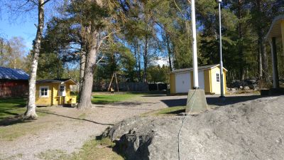 Gård på ett daghem. I förgrunden står en sten och en flaggstång. bakgrunden skymtar hus och träd.
