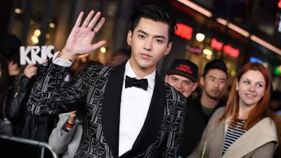Unga man i kostym vinkar till kameran. Pop- och filmstjärnan Kris Wu i Los Angeles i januari 2017.