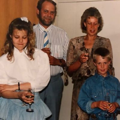 Anette med sin mamma, pappa och lillebror. Alla är festklädda och har ett champagneglas i handen.