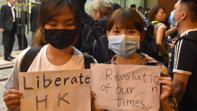 Två kvinnor håller upp skyltar där det står befria Hongkong, vår tids revolution.