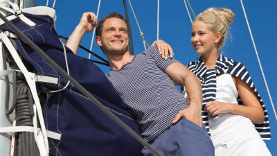 Man och kvinna står på en segelbåt och ser glada ut