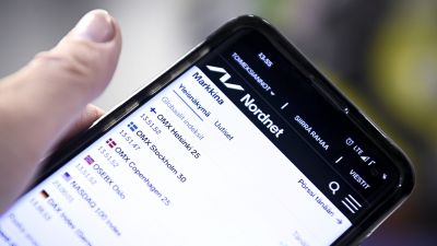 Hand håller i en smarttelefon och surfar på Nordnets sidor där olika globala index visas.