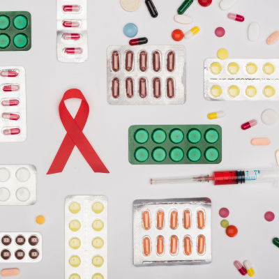 Grafik föreställande en aidsrosett, mediciner i pillserdform och en blodfylld spruta. 