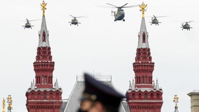 Militärhelikoptrar över Kreml under flyguppvisningen på segerdagen 9.5. En soldat i mask i förgrunden.