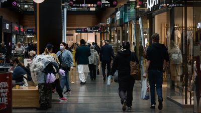 Mycket människor på rad i köpcentrum.