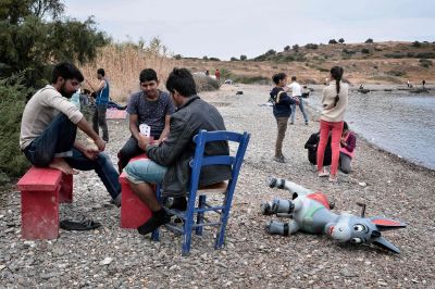 Flyktingar spelar kort på en strand på den grekiska ön Lesbos.