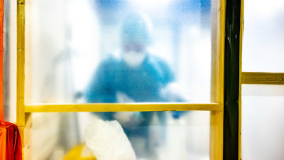 Sjukvårdare som arbetar med coronapatienter fotograferad genom glasdörr.