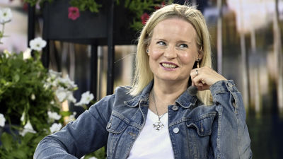 Riikka Purra ler och tittar åt sidan.