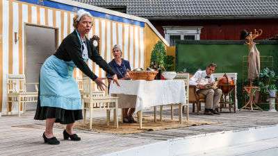 I framgrundern viftar rut och tittar ut mot publiken. Hon är klädd i gamla kläder som ett hembiträde kan tänkas använda. Bakom henne så sitter Regina och Agaton vid ett bord och tittar förundrande mot Rut.