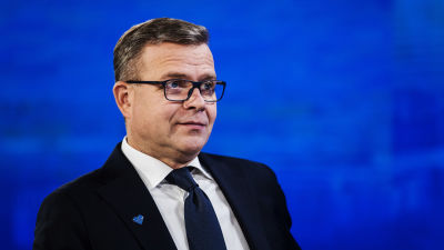 Petteri Orpo i kostym. Han tittar åt sidan. Han är fotograferad i Yles studio.