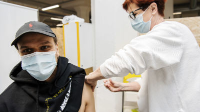 En kille vaccineras av en kvinna.