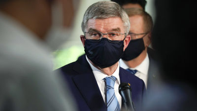 IOK:s ordförande Thomas Bach med munskydd, ser bekymrad ut