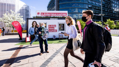 Socialdemokraternas valstuga i centrum av Helsingfors. Framför valstugan går en kvinna och en man med munskydd.