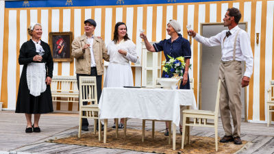 Pjäsens karaktärer höjer en skål vid middagsbordet.