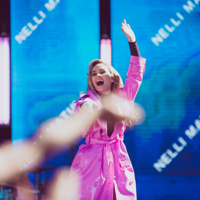Nelli Matula esiintymässä vaaleanpunaisessa trenssissä YleXPopissa 2018.