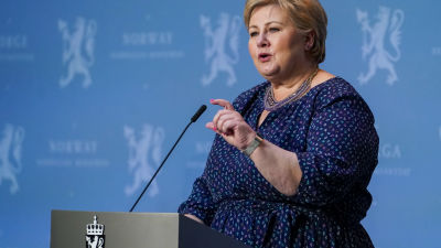 Erna Solberg står bakom ett podium och talar.
