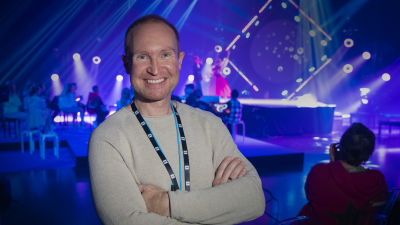 Sångcoachen Tomas Höglund poserar framför MGP-scenen.