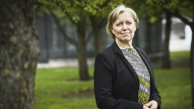 Maija Sakslin iklädd kavaj står i en park, halvkroppsbild.