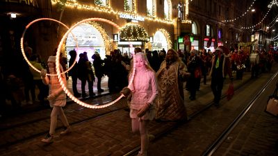 Personer med ringar med ljus går på Alexandersgatan i Helsingfors i en parad.