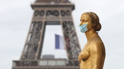Eiffeltornet och i förgrunden en staty - iförd ansiktsmask - på Trocadero Plaza.