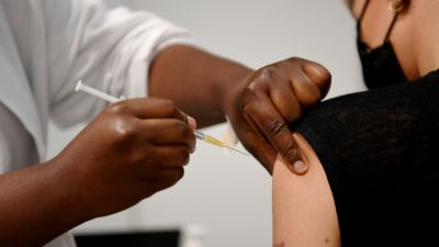 Närbild av en sjukskötare som ger vaccin åt en kvinna.