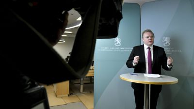 Antti Kurvinen står vid ett bord på en presskonferens.