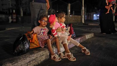 Palestinska barn sitter på en trottoar den 13 maj 2021. Palestinska familjer i Gaza har börjat fly sina hem.