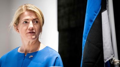 Eva-Maria Liimets står bredvid en estnisk flagga.