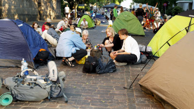 Demonstranter sitter på gatan bland tält.
