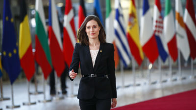 Statsminister Sanna Marin vid det föregående toppmötet i Bryssel. Hon går på den röda mattan, i bakgrunden EU-ländernas flaggor. 