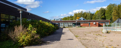 Tom skolgård vid en skolbyggnad i rött tegel.