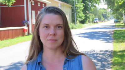 Kvinna poserar på gata i sommarstad.