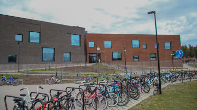 En grå och en tegelröd byggnad med cyklar intill.