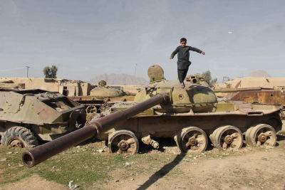 En afghansk pojke står på det som finns kvar av en stridsvagn från sovjeteran