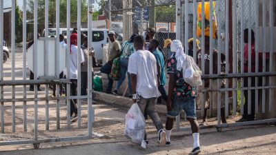 Migranter går igenom en port.