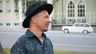 Man i svart hatt står vid en gata.