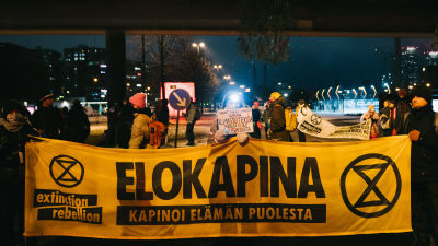 Mielenosoittajat pitelevät keltaista lakanaa, jossa lukee Elokapina kapinoi elämän puolesta.
