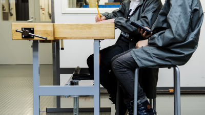 Två högstadieelever sitter vid ett slöjdbord.