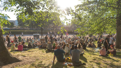 Människor sitter i en fullsatt park.
