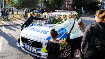 Människor lägger blommor på en polisbil i Göteborg