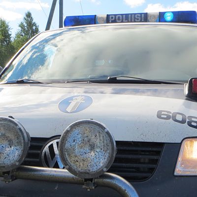 Poliisiauto parkissa vilkut päällä.