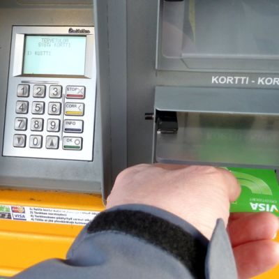 Mies laittaa pankkikorttia tankkausautomaattiin