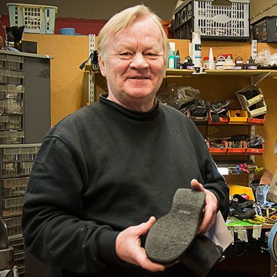Arto Aronen liikkeessään, tavarahyllyjä, oikeassa kenkien käsittelykone