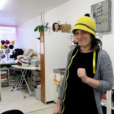 Nainen seisoo myymälässä hattu päässä