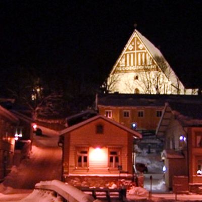 Porvoon vanha tuomiokirkko kohoaa juhlavalaistuksessa alempana olevien puutalokortteleiden yläpuolelle.