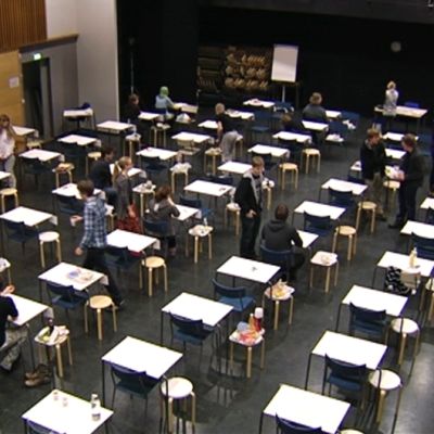 Ylioppilaskirjoitukset alkamassa koulun salissa.