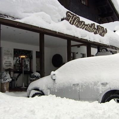 Lumeen peittynyt auto majatalon edessä