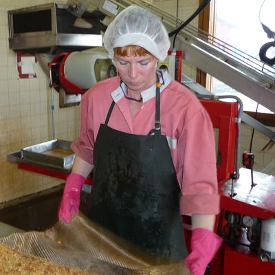 Mehuaseman hoitaja puhdistaa mehunpuristuksessa käytettäviä liinoja.