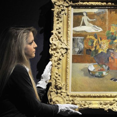 Huutokauppa Christie’sin työntekijä esittelee Paul Gauguinin teosta Nature morte a 'L'Esperance.